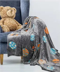 Children’s glow in the dark space fleece blanket glowing softly in low light, ideal for bedtime and bedrooms
