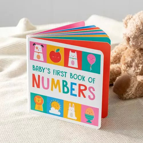 babys first numbers book resting on a childs bed beside a soft toy, early learning board book for babies and toddlers