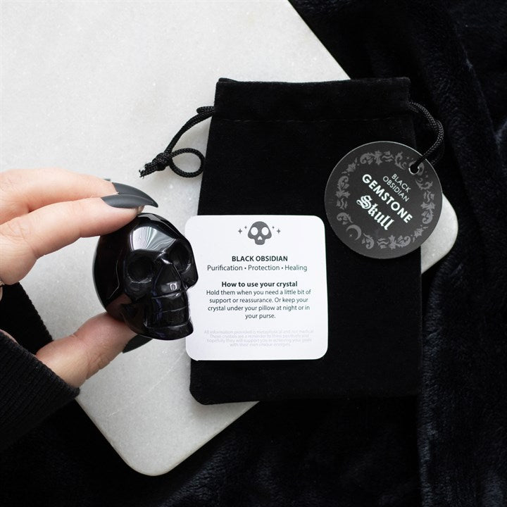black obsidian crystal skull displayed with drawstring pouch in atmospheric home setting