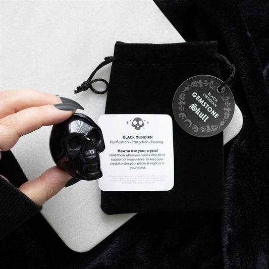 black obsidian crystal skull displayed with drawstring pouch in atmospheric home setting
