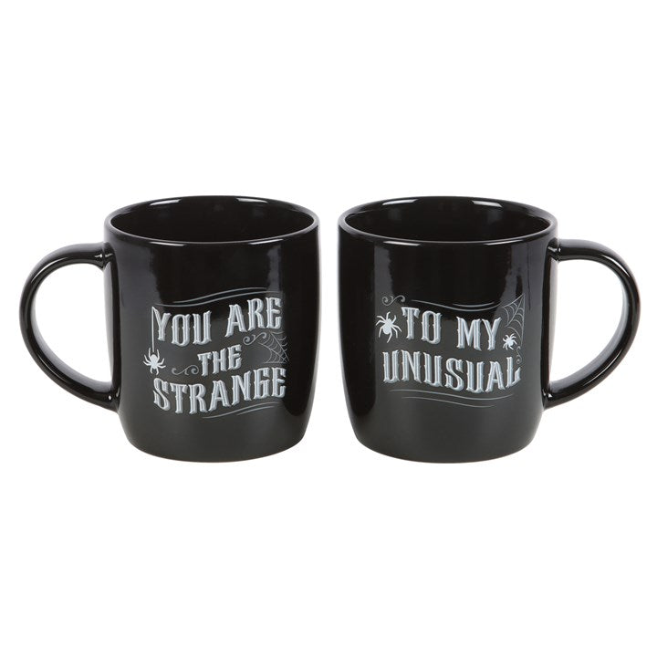 matching gothic couple mugs shown together displaying you are the strange text