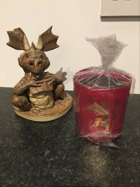 game of thrones lannister candle styled in home setting beside stone dragon ornament